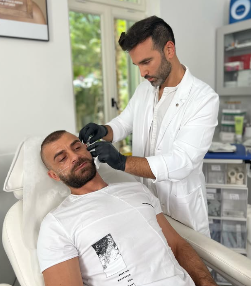 ד״ר ארי שרון בחלוק לבן במהלך טיפול במטופל בקליניקה